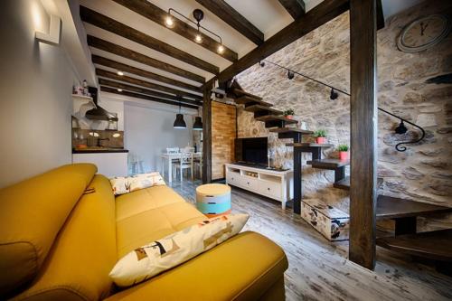 a living room with a yellow couch and a kitchen at RIVA SUITE 2 in Komiža