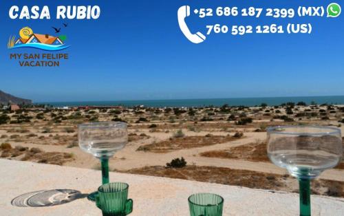 two wine glasses sitting on a table with a view of a desert at Casa Rubio del Mar - Monthly Rentals Welcome in San Felipe