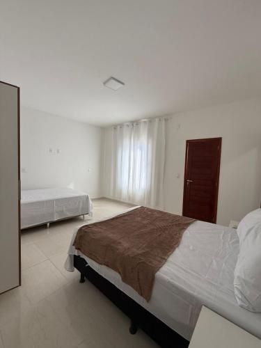 a bedroom with two beds and a dresser at Pousada Essencia de Pipa in Pipa