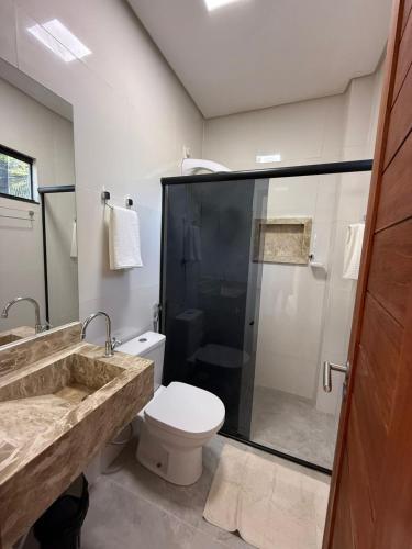a bathroom with a shower and a toilet and a sink at Pousada Essencia de Pipa in Pipa