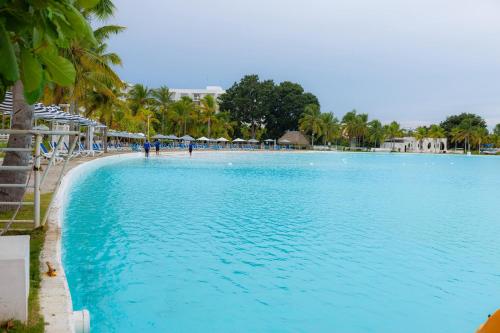 a large swimming pool next to a beach with palm trees at Relax Loft on the beach Town Center Playa B in Río Hato