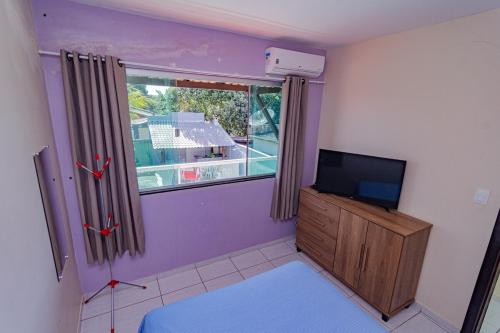 a living room with a tv and a window at Casa de Verão, 04 quartos, 03 banheiros, piscina e churrasqueira para relaxar in Pirapora