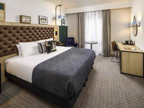 a hotel room with a large bed and a desk at Mercure Oxford Hawkwell House Hotel in Oxford