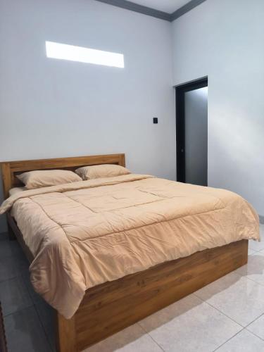 a bed in a white room with a wooden bed frame at Gama Stay in Lovina