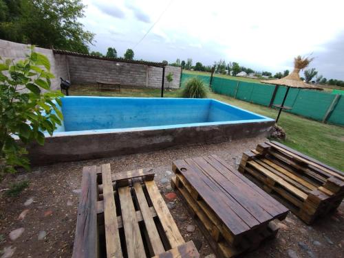a blue swimming pool with a bench and a table at Cabañas Rústicas Entre Montañas in Tunuyán