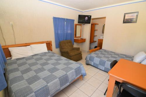 a bedroom with two beds and a chair and a television at San Felipe Rental Studio #1 Free WiFi and Cable TV in San Felipe