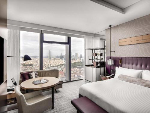 a hotel room with a bed and a desk and a table at Fairmont Quasar Istanbul Hotel in Istanbul
