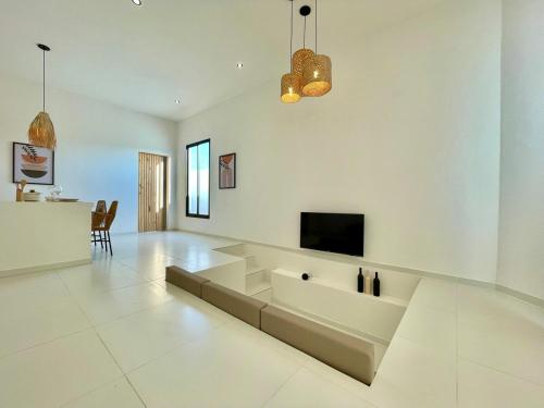 a white living room with a couch and a tv at Casa com piscina privativa Praia da Pipa #2 in Tibau do Sul