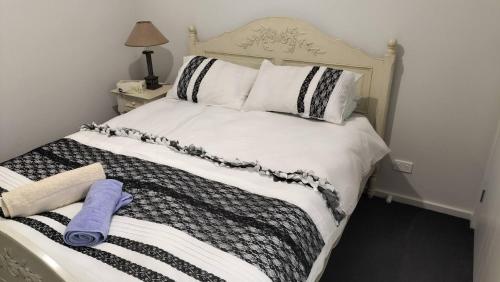a bed with black and white sheets and pillows at 5 mins to Lake Macquarie, 30 to Hunter Wineries in Teralba