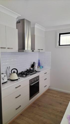 a kitchen with white cabinets and a stove top oven at 5 mins to Lake Macquarie, 30 to Hunter Wineries in Teralba