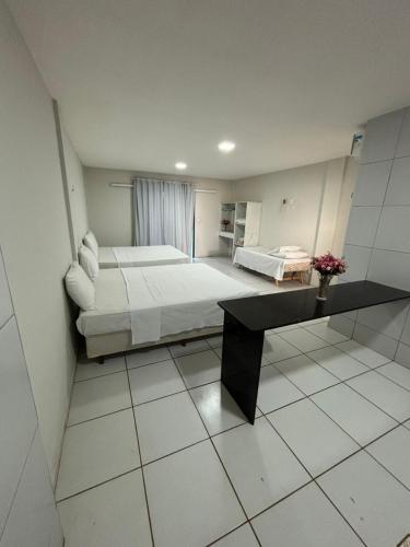 a bedroom with a bed and a table in it at Pousada Lessence By Solarium in São Miguel do Gostoso