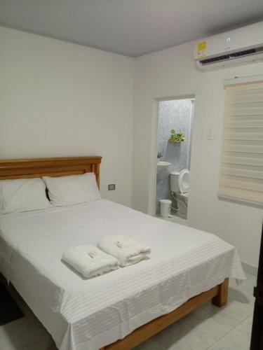 a bedroom with a white bed with towels on it at Casa Isabel in Santa Cruz de Mompox