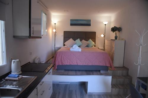 a bedroom with a bed with pink sheets and a sink at Tabua Village Madeira Suite VIP in Ribeira Brava