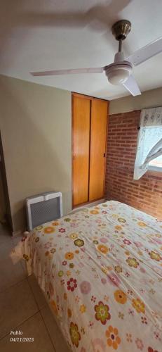 ein Schlafzimmer mit einem Bett mit geblümter Tagesdecke in der Unterkunft Cabañas Don Lelio 2 in Mina Clavero