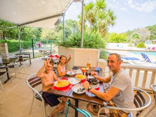 a man and two children sitting at a table at Chalet 6 pers, 2 ch, Terrasse, Équipements Bébé - API-1-52-708 in Sainte-Eulalie-en-Born