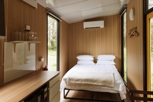 a small bedroom with a bed and a window at Yarriabinni Escape 2 by Tiny Away in Stuarts Point