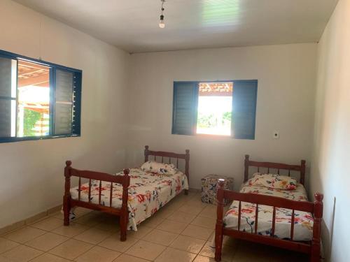 een slaapkamer met twee bedden en twee ramen bij Hotel fazenda Monte Verde in Uberlândia
