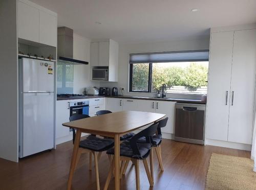 a kitchen with white cabinets and a wooden table at Homestead Hideaway in Ohoka in Ohoka