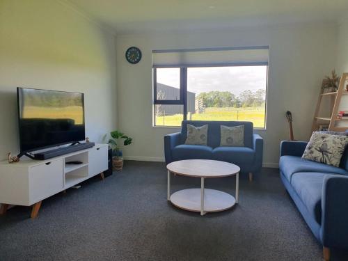 a living room with a couch and a tv and a table at Homestead Hideaway in Ohoka in Ohoka