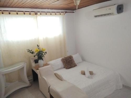 a bedroom with a white bed with a couch and a window at Apartamento a 15 Min del centro in Cartagena de Indias