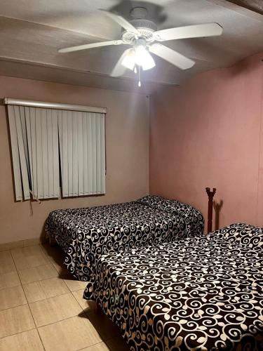 two beds in a room with a ceiling fan at Casa Abundia in La Calera