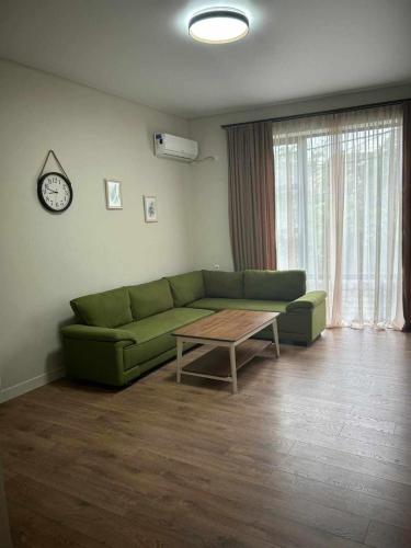 a living room with a green couch and a table at Hotel Kutaisi Globus in Kutaisi