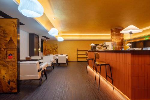 a restaurant with a bar with white chairs and tables at Chongqing INS·Wanbai Terrace River View Hotel (Jiefangbei Hongyadong Branch) in Nan'an