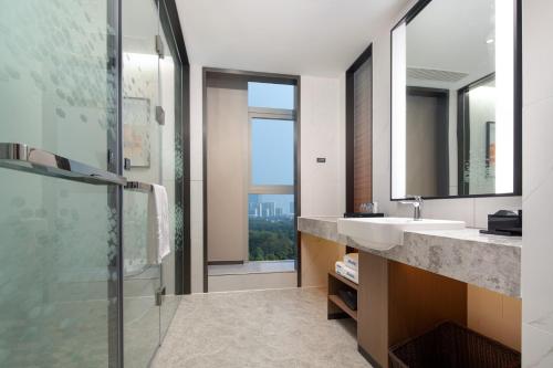 een badkamer met een wastafel en een douche met een raam bij Hampton by Hilton Hefei Binhu in Hefei