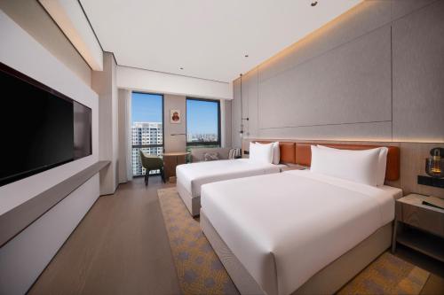 a hotel room with two beds and a flat screen tv at Holiday Inn Beijing Daxing Centre by IHG in Beijing