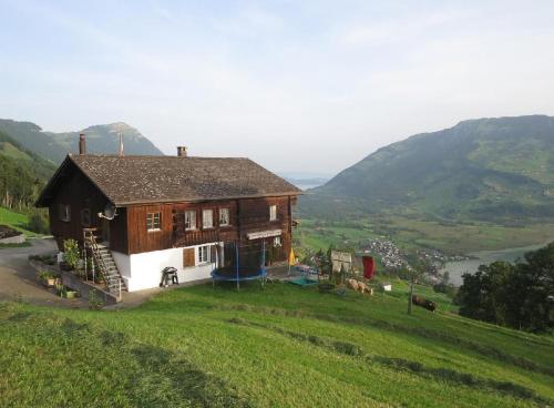 a house on top of a hill with a green field at Biohof Langberg in Lauerz