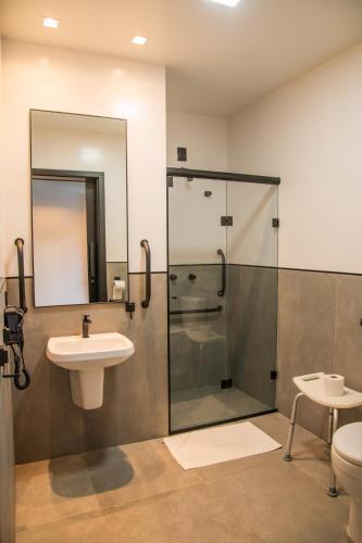 a bathroom with a shower and a sink and a toilet at Coroados Hotel & Flats in Nova Prata