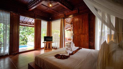 um quarto com uma cama grande e uma televisão. em Ubud Heaven Sayan em Ubud
