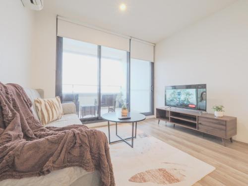 a living room with a couch and a tv at 3BR2BA apt in FootscaryPoolCAR PARKwifi in Melbourne