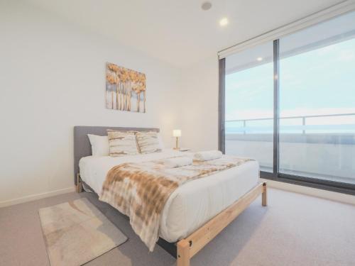 a bedroom with a large bed and a large window at 3BR2BA apt in FootscaryPoolCAR PARKwifi in Melbourne