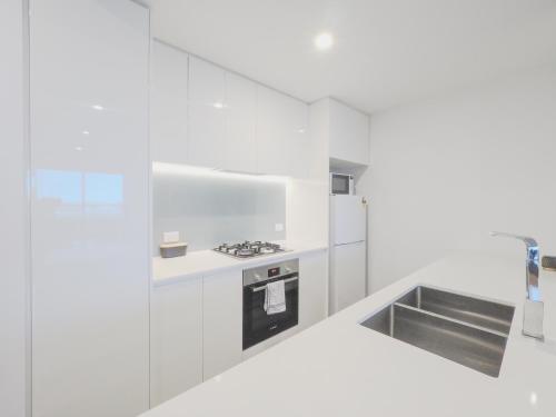 a white kitchen with a stove and a sink at 3BR2BA apt in FootscaryPoolCAR PARKwifi in Melbourne