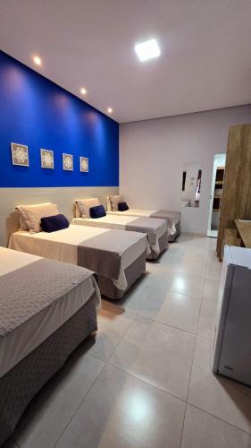 a room with four beds and a blue wall at Araguaia Plaza Hotel in Conceição do Araguaia