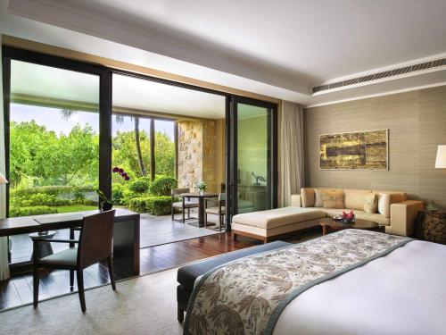 a bedroom with a bed and a desk and a room at Raffles Hainan Clear Water Bay in Sanya