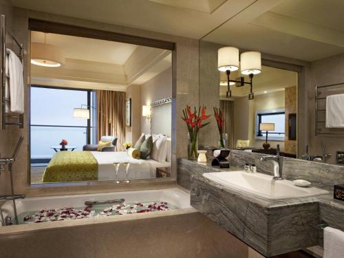 Un baño con una cama, una bañera y un lavabo. en Fairmont Yangcheng Lake, en Kunshan