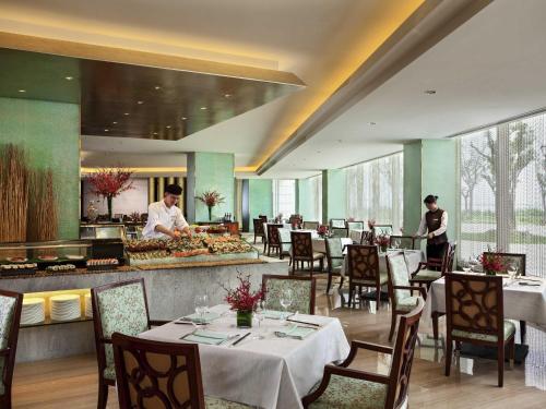 een restaurant met tafels en een chef-kok die maaltijden bereidt bij Fairmont Yangcheng Lake in Kunshan