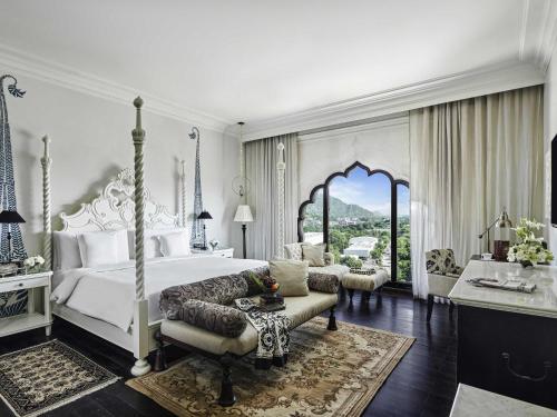 a bedroom with a white bed and a couch and a table at Fairmont Jaipur in Jaipur