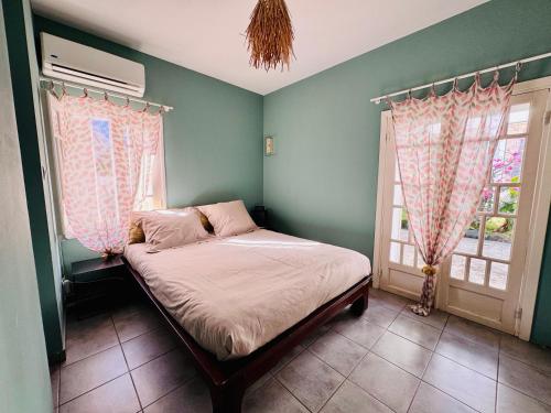 a small bedroom with a bed and two windows at Maisonette de Charme à Terre Sainte in Saint-Pierre