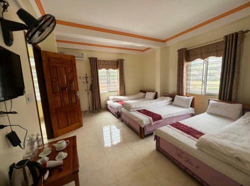 a bedroom with two beds and a television in it at Khách Sạn Mai Đào in Mèo Vạc