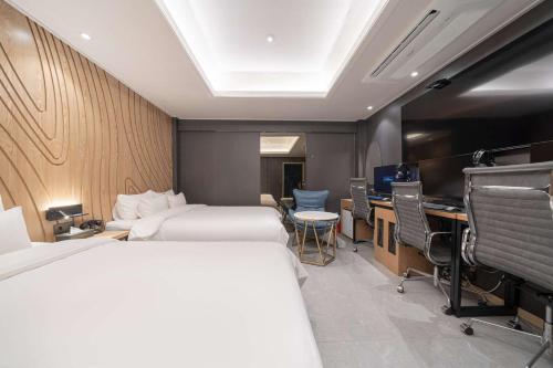 Una habitación de hotel con dos camas, un escritorio y una computadora. en From H About Hotel Chungju, en Chungju