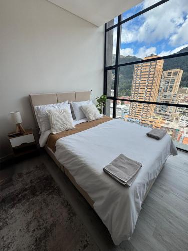 Un dormitorio con una cama grande con una ventana grande. en Modern apartment with a beautiful panoramic view, en Bogotá