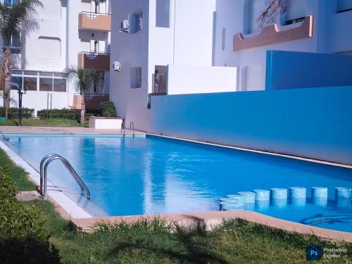 a large blue swimming pool next to a building at Superbe Appartement avec vue paronamique sur la plage Achakar - proche de Cap Spartel - Grottes Hercule N2 in Tangier