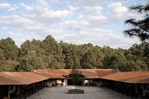 a group of buildings with trees in the background at Hotel Puerta de Piedra in Tapalpa