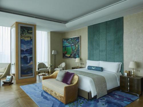 a bedroom with a large bed and a chair at Raffles Jakarta in Jakarta