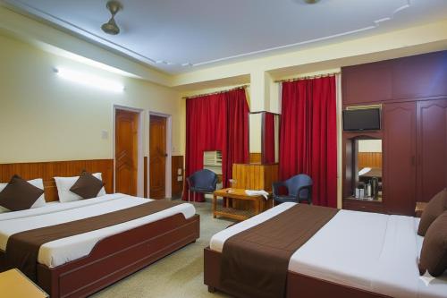 a hotel room with two beds and red curtains at Raghunath Jammu in Jammu