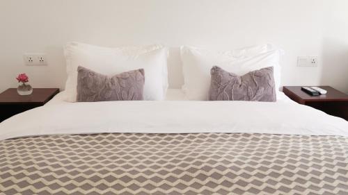 a large white bed with two pillows and two tables at Serenity Angkor in Phum Pobos