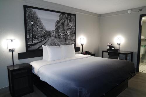 een slaapkamer met een groot wit bed met een foto aan de muur bij Super 8 by Wyndham Savannah in Savannah